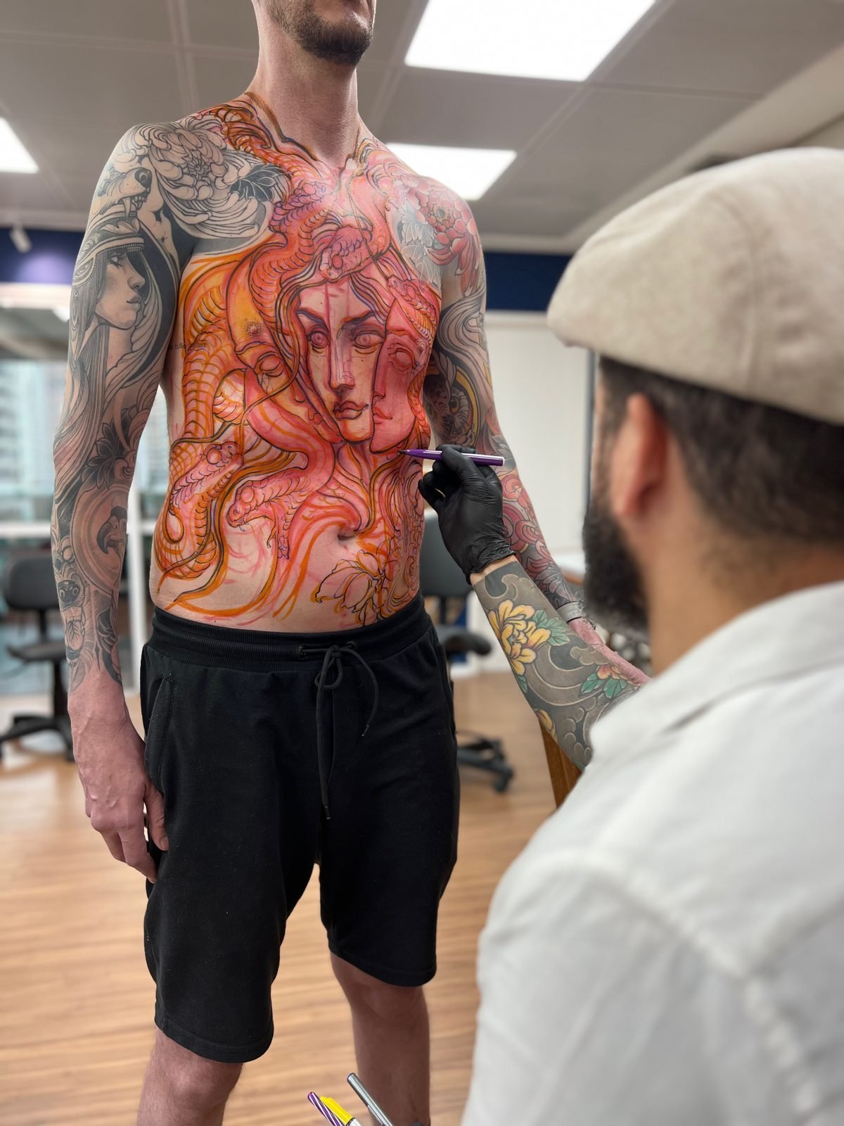 Denis desenhando a composição diretamente no corpo antes da tatuagem